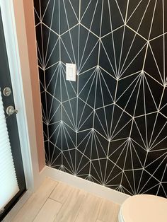 a white toilet sitting next to a black wall with geometric designs on it's walls