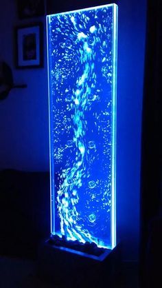 a blue light that is on top of a stand in the dark with water and bubbles