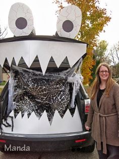 a woman standing in front of a car decorated like a monster