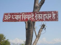 a red and white sign hanging from the side of a tree