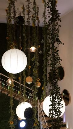 the lights are hanging from the ceiling in the room with plants and flowers on it