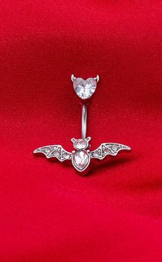 This breathtaking white gold plated bat belly ring is a subtly spooky addition to any ghouls belly jewellery rotation. Featuring a clear, sparkling zircon bat & heart -this piece is as glamorous as it is ghostly. Material: White Gold Plated Surgical Steel Type: Belly Ring. Gauge: 14G. Length: 10mm. Colour: Silver Suitable Piercing: Upper Belly Button Spider Belly Button Piercing, Cool Belly Rings, Belly Jewellery, Cute Belly Rings, Belly Button Piercing Jewelry, Belly Piercing Jewelry, Belly Piercing Ring, Cool Piercings, Belly Jewelry