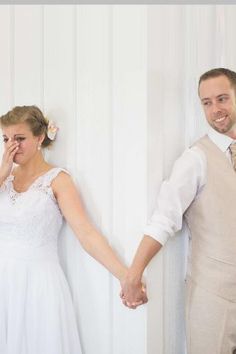 a bride and groom holding hands in front of a white wall