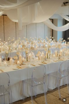 the tables are set up with white flowers and candles for an elegant wedding reception or special event