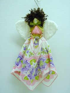 an angel ornament hanging from a hook on a white wall with purple and green flowers