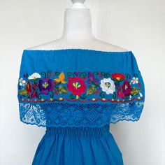 This Beautiful Off the Shoulder Mexican Dress is the perfect dress to add to your wardrobe. It’s lightweight with elastic around the shoulders/waist and is hand embroidered with vibrant florals in front of the neckline and the bottom area. Lace accents added for a more feminine look. MADE IN MEXICOBy: Mexican ArtisansFor: Women Size: Medium (view size chart) Color: blue | multiDetails: Material: Cotton manta fabric Embroidered thread Calve Length Elastic shoulders Elastic waist Lace Washing Inst Cotton Vacation Dresses With Floral Embroidery, Fitted Floral Embellished Maxi Dress For Summer, Summer Festival Maxi Dress With Floral Embroidery, Blue Floral Embroidery Summer Dress, Blue Floral Embroidered Summer Dress, Cotton Sundress With Floral Embroidery, Vacation Sundress With Floral Embroidery, Cotton Maxi Sundress With Floral Embroidery, Blue Floral Embellished Summer Dresses