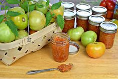 apples, tomatoes, and other fruit are on the table next to jars with jams in them