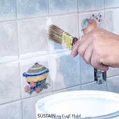 a person using a brush to paint tiles