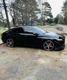 a black car parked on the side of a road next to some grass and trees