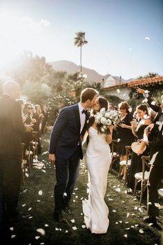 a bride and groom are walking down the aisle as confetti is thrown around them