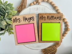 two wooden frames with neon green and pink sticky notes attached to them, sitting next to a potted plant