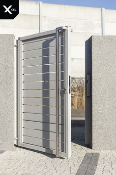 an open metal door with bars on the sides and side by side concrete walls behind it