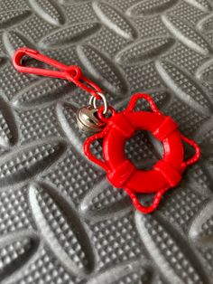 a red keychain with a metal hook on it's end sitting on a gray surface