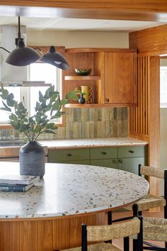 a kitchen with wooden cabinets and an island in the middle is decorated with green plants