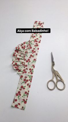 a pair of scissors sitting next to a flowered tie with the word alca com bazadinthrol on it