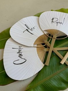 three fan shaped fans sitting on top of a green leaf covered table next to a wall