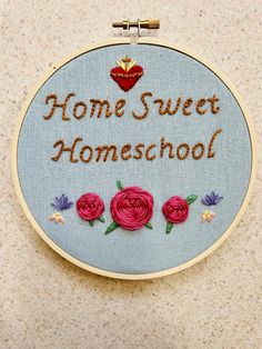 embroidered hoop hanging on the wall that says home sweet homeschool with three roses