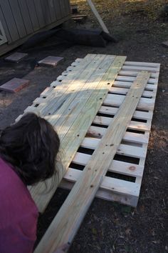 a person kneeling down next to a pallet with wood planks on the ground