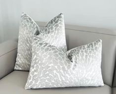 two pillows sitting on top of a gray couch