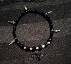 Add a little alternative goth touch to your look! (already gorgeous and unique The contrast of the black and silver pearls as well as the 5 small studs, add style to your wrist and your outfit🖤 A pretty black butterfly charm 🦋 adds the romantic finishing touch! *Elastic bracelet of approximately 18cm. *Can be customized and made smaller or larger: leave me the desired size in a message. *6mm and 4mm black agate beads *4mm silver plated hematite beads. *Black butterfly charms in black metal all Goth Bead Bracelet, Black Edgy Bracelets As Gift, Edgy Black Bracelet For Festivals, Edgy Black Bracelet For Festival, Black Grunge Bracelets For Festivals, Edgy Black Festival Bracelet, Alternative Style Black Bracelets As Gift, Edgy Black Beaded Jewelry, Alternative Style Black Bracelet Gift