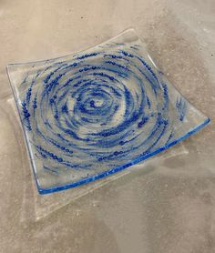 a blue and white glass dish with swirl designs on the bottom, sitting on a table