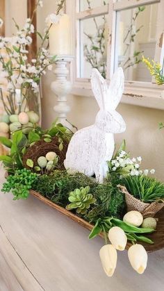 a wooden tray filled with plants and fake eggs on top of a table next to a mirror