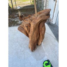 a piece of wood sitting on top of a cement floor next to a green bag