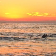 two surfers in the ocean at sunset