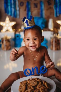 a young boy sitting in front of a plate of cookies with the word one on it