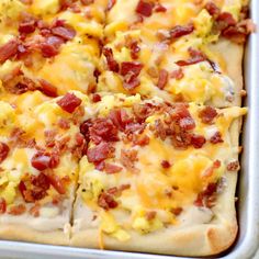 a square pizza with cheese and bacon on it