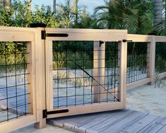 a wooden fence with metal bars on the top and bottom, in front of palm trees