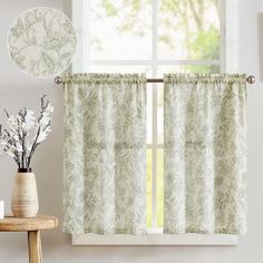 a window with curtains and flowers on the table next to it in front of a mirror