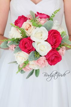 a bride holding a bouquet of red, white and pink flowers