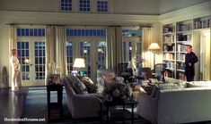 a living room filled with lots of furniture next to a window covered in bookshelves