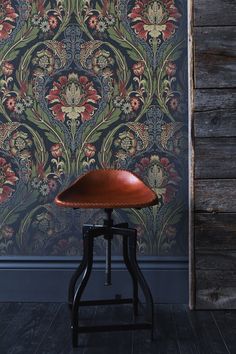 an old fashioned stool in front of a wallpapered background