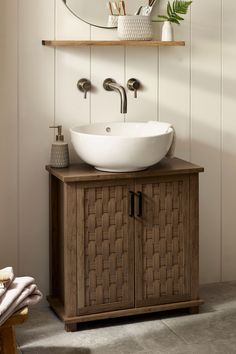 a bathroom vanity with a round mirror above it and a bowl sink on the counter