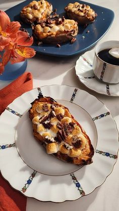 two plates with desserts on them next to a cup of coffee