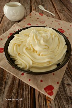 a bowl filled with white frosting sitting on top of a wooden table