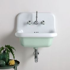 a white sink sitting on top of a green table next to a potted plant