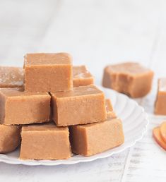 a white plate topped with pieces of brown fudge next to sliced oranges on a table