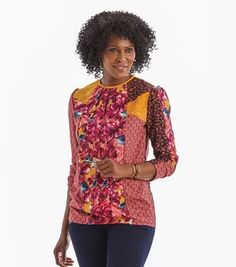 a woman with an afro standing in front of a white background wearing blue jeans and a pink top