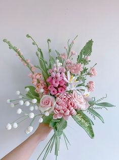 a hand holding a bouquet of pink and white flowers