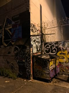 a wall covered in graffiti next to a fence