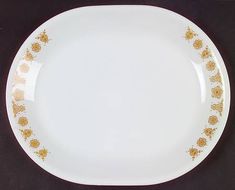 an empty white plate with gold designs on the rim and bottom, sitting on a black surface