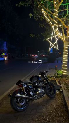 a motorcycle parked next to a tree with lights on it