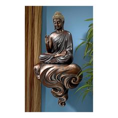 a buddha statue sitting on top of a table next to a potted plant