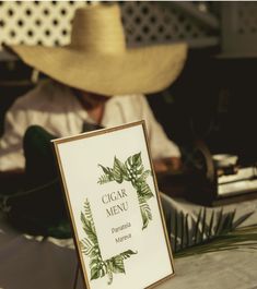 a sign sitting on top of a table next to a straw hat and palm tree