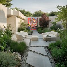 an outdoor garden with white couches and colorful art on the wall behind it, surrounded by greenery