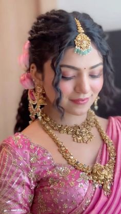 a woman in a pink sari with gold jewelry on her neck and headpiece