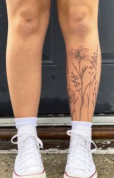 a woman's legs with tattoos on them and white tennis shoes in front of a door